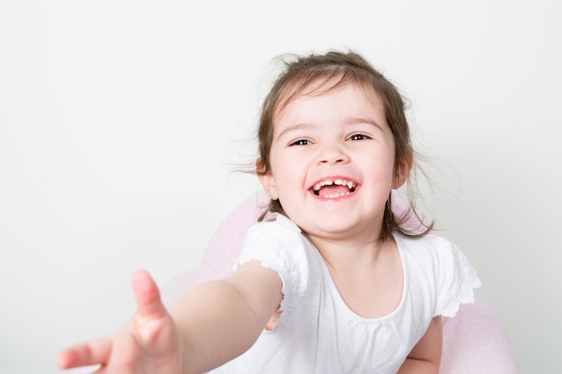 Foto retrato de adorável sorrindo brincando de garotinha divertida isolada em branco