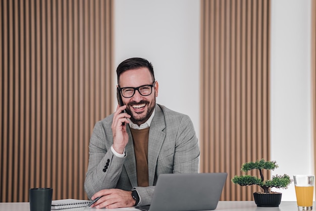 Retrato de adorável trabalhador de escritório elegante falando no telefone