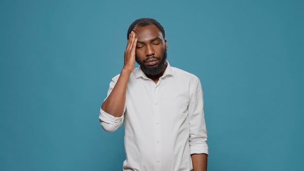 Retrato de adulto chateado lidando com dor de cabeça e enxaqueca, esfregando as têmporas para curar a dor e o sofrimento. Pessoa doente estressada se sentindo mal e triste com a dor física, esperando para resolver o problema.