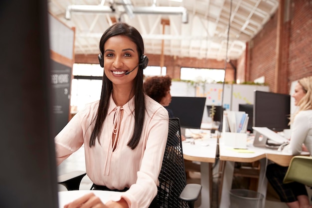 Retrato de agente de atendimento ao cliente feminino trabalhando na mesa no call center