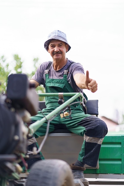 Retrato de agricultor satisfeito sentado ao volante de um trator de duas rodas