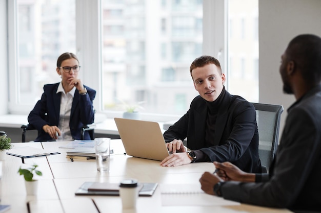 Retrato de alto ângulo de empresária de sucesso usando cadeira de rodas enquanto lidera reunião de negócios no escritório com diversos grupos de pessoas