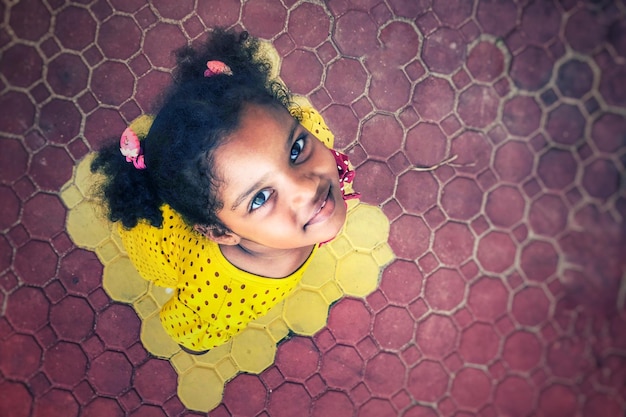 Retrato de alto ângulo de menina sorridente de pé em uma pedra de pavimentação