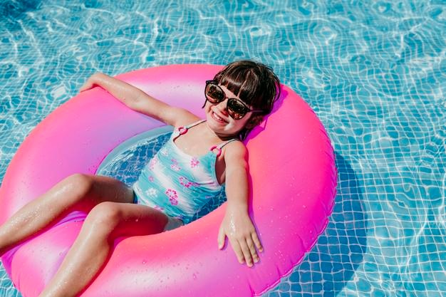 Retrato de alto ângulo de sorriso relaxando em anel inflável na piscina