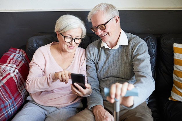 Retrato de alto ângulo de um casal sênior sorridente usando smartphone no espaço da cópia do lar de idosos