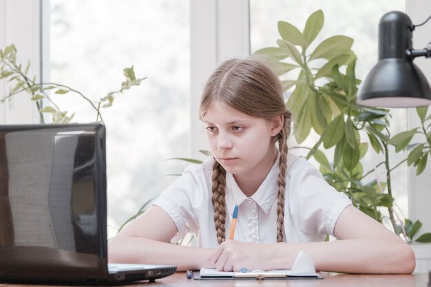 Retrato de aluna gostando de aprender no escritório de coworking usando computador portátil para pesquisa, freelancer durante a realização de projetos para trabalho remoto, fazendo anotações. Aluno concentrou notas de desenho