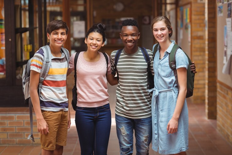 Foto retrato de alunos felizes em pé e com os braços no corredor