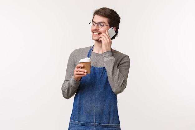 Retrato de amigável alegre jovem empregado do sexo masculino no avental