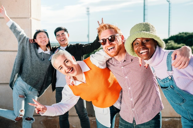 Retrato de amigos adolescentes multirraciais alegres posando para a câmera ao ar livre sorrindo e rindo aproveitando o tempo juntos