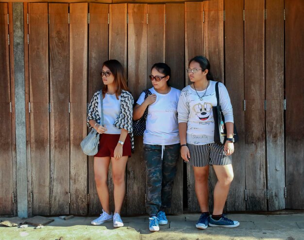 Foto retrato de amigos de pé contra uma parede de madeira