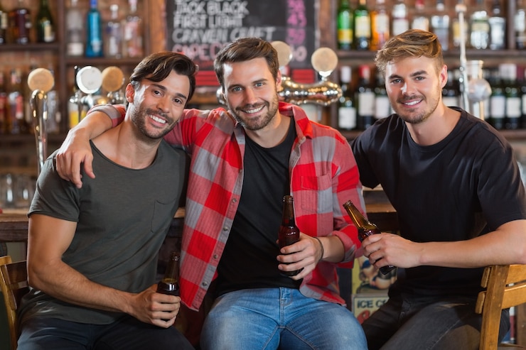 Foto retrato de amigos homens sorridentes segurando garrafas de cerveja em bar