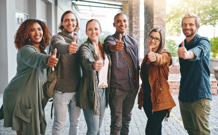Foto retrato de amigos ou estudantes com os polegares para cima na universidade para revisão ou feedback na aprendizagem ou educação voto escolar ou pessoas com "sim" assinar ou ok para acordo unidade ou trabalho em equipe no campus