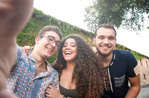 Foto retrato de amigos sorridente de pé contra as árvores