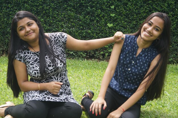 Foto retrato de amigos sorridente sentados em um campo de grama no parque