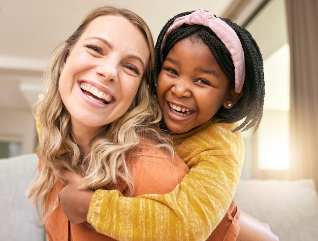 Retrato de amor e família com uma menina adotada e mãe adotiva se unindo na sala de sua casa Sorriso facial e pegando carona com uma mulher e filha em sua casa junto com um sorriso