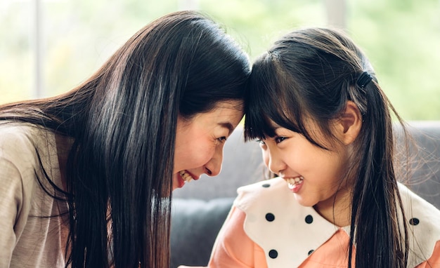 Retrato de amor feliz mãe de família asiática e criança de meninas asiáticas sorrindo e se divertindo tocando o rosto com momentos bonitos de filha de criança bons momentos