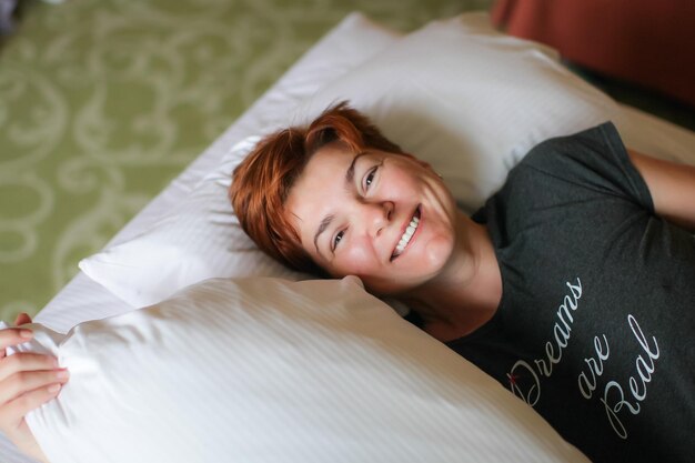 Retrato de ângulo alto de mulher madura sorridente deitada na cama em casa