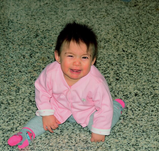 Retrato de ângulo alto de um bebê chorando sentado no chão em casa