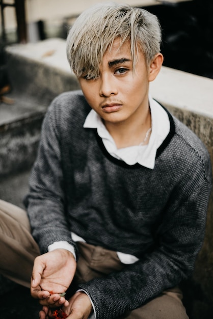 Retrato de ângulo alto de um jovem sentado junto a uma parede de contenção