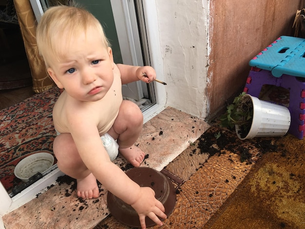 Foto retrato de ângulo alto de um menino bonito agachado na porta