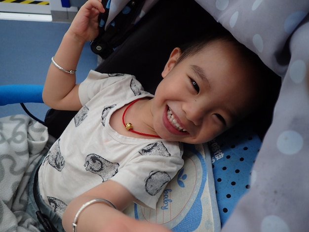 Foto retrato de ângulo alto de um menino bonito sorridente sentado em um carrinho de bebê