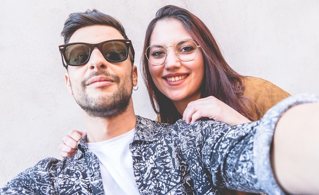 Foto retrato de ângulo baixo de um jovem casal sorridente de pé contra a parede