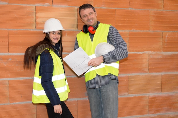 Retrato de arquiteto masculino e mulher discutindo o plano no canteiro de obras