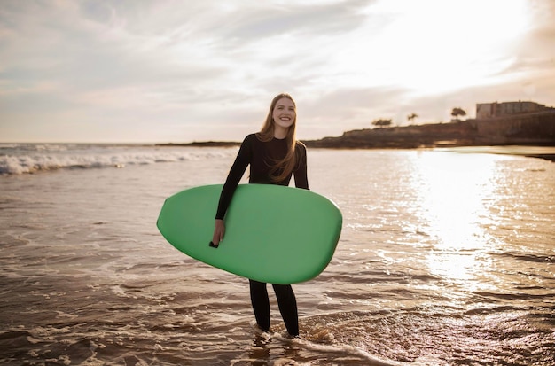 Retrato de atividades esportivas de uma jovem surfista alegre posando com prancha de surf