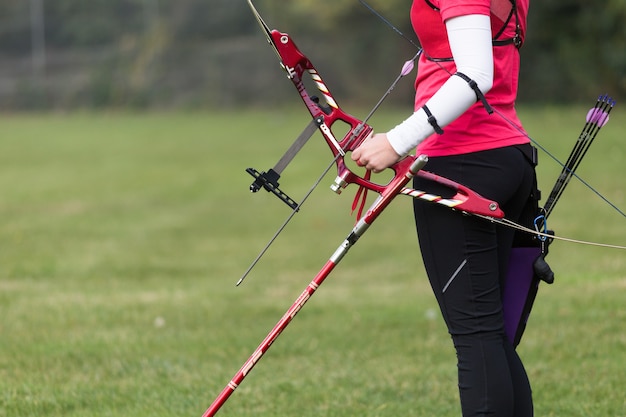 Retrato de atleta feminina praticando arco e flecha no estádio.