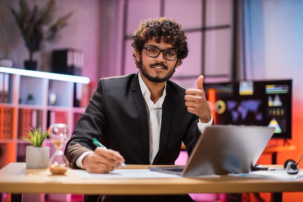 Retrato de atraente e confiante gerente de escritório especialista em TI barbudo vestindo terno usando laptop