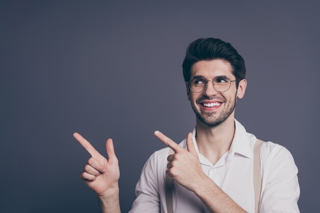 Retrato de atraente empresário bem sucedido líder indicando dedos espaço vazio boas notícias vestido formalwear camisa bege suspensórios calças especificações.