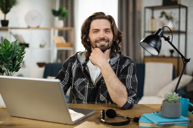 Retrato de atraente especialista em TI masculino digitando no teclado do laptop moderno