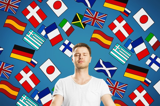Foto retrato de atraente jovem europeu meditando com desenhos abstratos de bandeiras coloridas tradução de viagens e conceito de aprendizado de idiomas