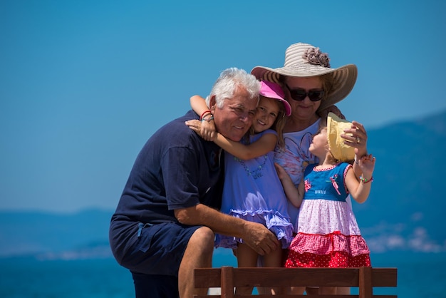 retrato de avós felizes com netas bonitinhas se divertindo em um banco à beira-mar durante as férias de verão Conceito de férias em família saudável