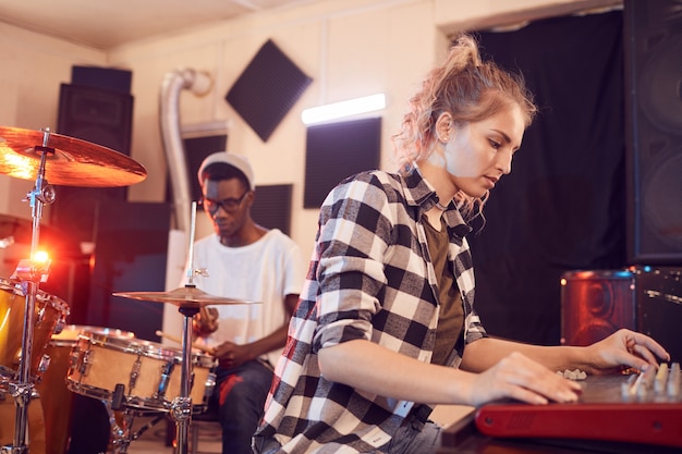 Foto retrato de banda contemporânea escrevendo música em estúdio de gravação com foco em jovem