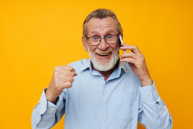 Retrato de barba cinzenta de homem idoso com óculos falando ao telefone inalterado