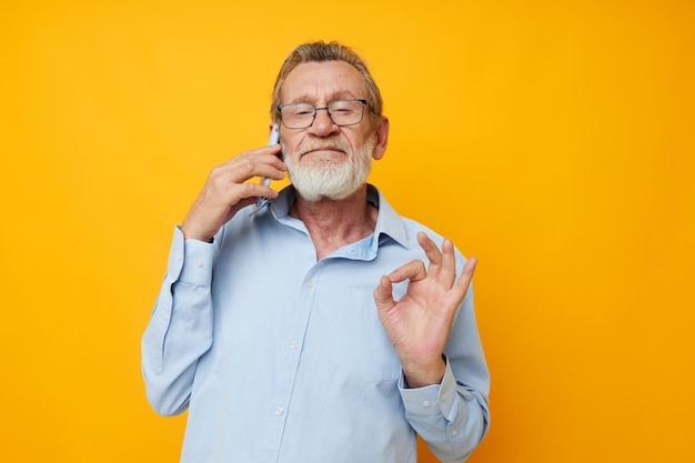 Retrato de barba cinzenta de homem sênior feliz com óculos falando ao telefone vista recortada