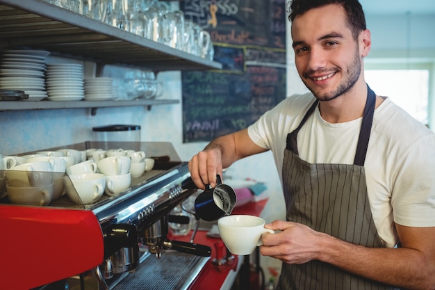 Retrato de barista feliz derramando café no café