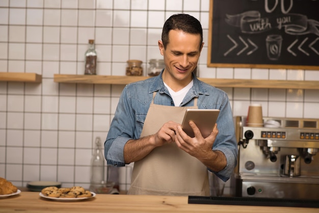 Retrato de barista sorridente usando tablet digital no café