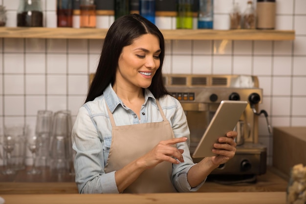 Retrato de barista sorridente usando tablet digital no café