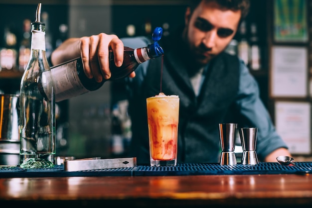 Retrato de barman derramando calda de cereja em detalhes de coquetel de verão laranja do bar e restaurante