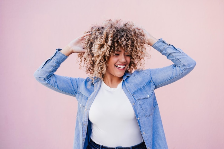 Foto retrato de bela curva mulher hispânica afro cabelo ao ar livre na primavera rosa parede corpo positividade