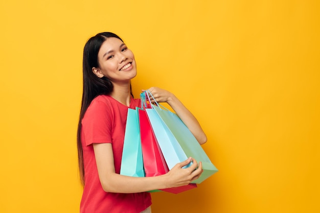 Retrato de belas sacolas de compras asiáticas em camiseta vermelha isolada de fundo inalterado