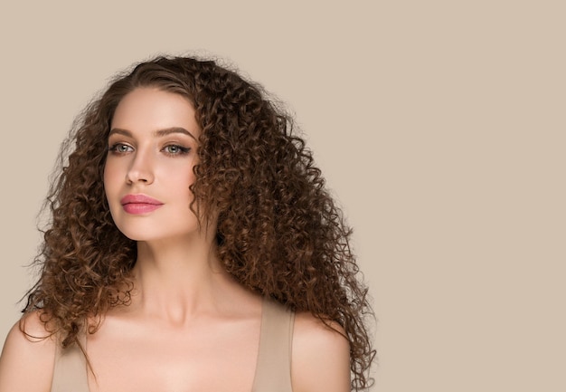 Retrato de beleza de mulher de cabelo moreno longo encaracolado, rosto de glamour feminino. Cor de fundo marrom