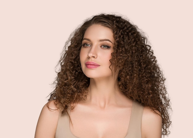 Retrato de beleza de mulher de cabelo moreno longo encaracolado, rosto de glamour feminino. cor de fundo rosa