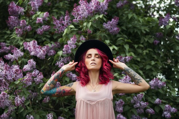 Retrato de beleza de primavera linda garota com cabelo vermelho em ramos desabrocham lilás