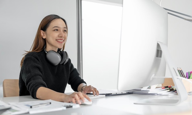 Retrato de belo freelancer asiático usando computador desktop no escritório doméstico