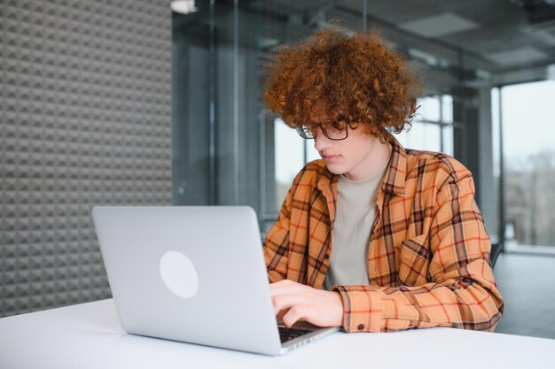 Foto retrato de blogueiro milenar alegre com tecnologia moderna de celular e laptop, desfrutando de estilo de vida freelance, cara hipster feliz em óculos ópticos usando telefone celular e netbook no café de rua