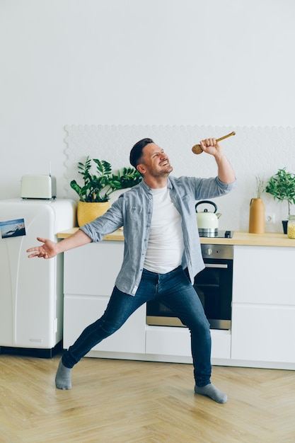 Retrato de bobo se divertindo na cozinha cantando na dança da colher