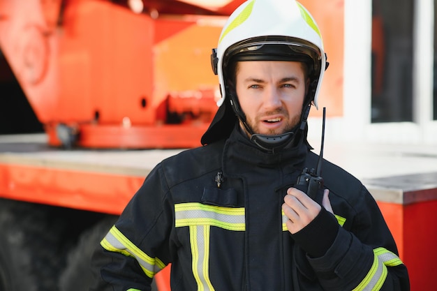 Retrato de bombeiro de plantão Foto bombeiro com máscara de gás e capacete perto do carro de bombeiros